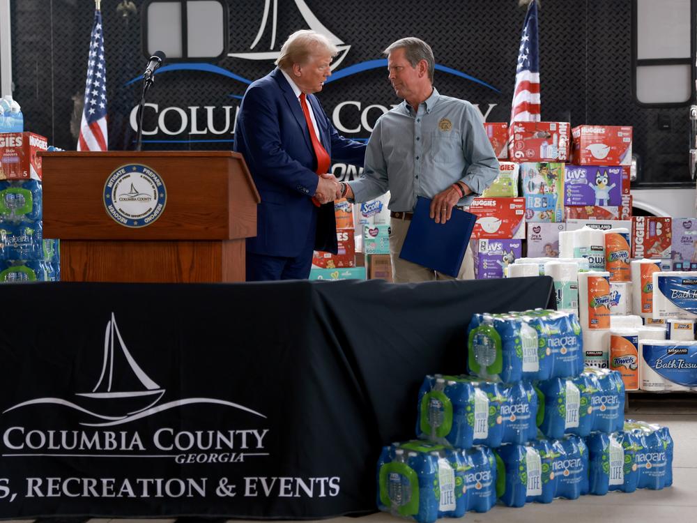 Republican presidential nominee, former President Donald Trump, and Georgia Gov. Brian Kemp shake hands as they visit the area while it recovers from Hurricane Helene on Oct. 04 in Evans, Ga.