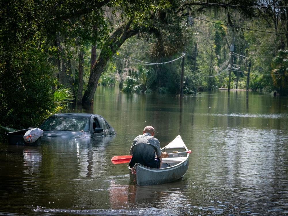 After speaking with members of Hillsborough County Fire Rescue, a man paddles back into a flooded neighborhood in Valrico, Fla. Flooding from a nearby waterway turned some neighborhoods into rivers, forcing dozens to evacuate their homes.