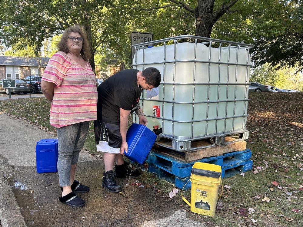 Teresa Thomas (left) and her son David Murray fill up plastic containers with gray water at the apartment complex in Asheville where she lives.