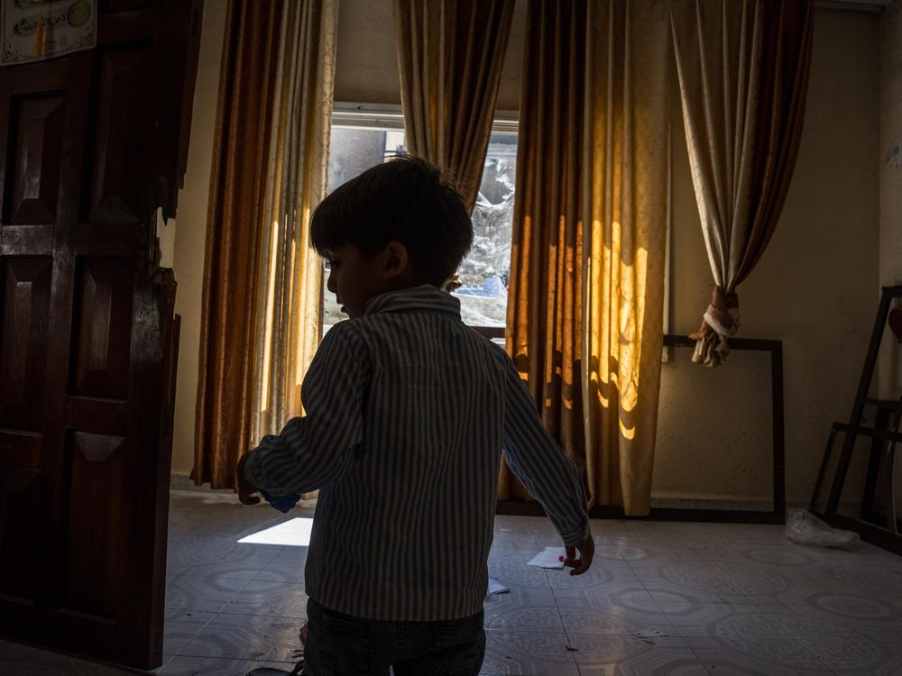 Three-year-old Sami Abu Ali, grandson of Raeda Abu Ali, plays beside a door that was broken by Israeli soldiers in his family's home in the Jenin refugee camp, Sept. 18.