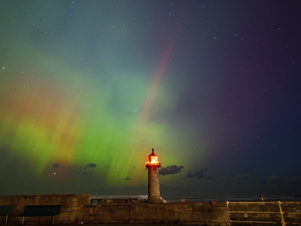 The northern lights, also known as the aurora borealis, are seen in the sky across Whitby Harbour, Whitby, UK, on Oct. 10.