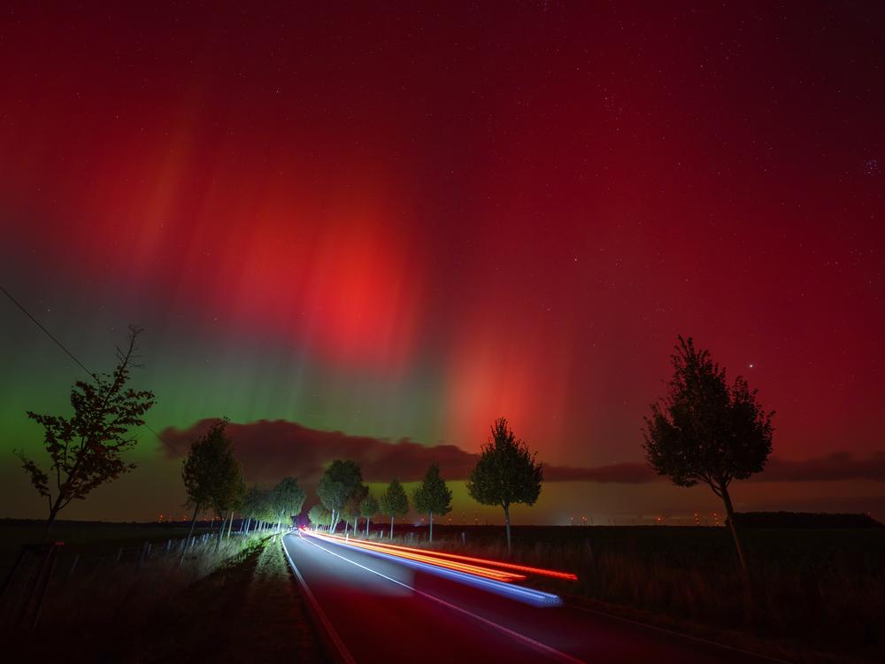 Northern lights glow in the night sky above a road in eastern Brandenburg, Germany.