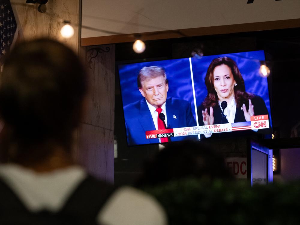 A person stops to watch a screen in Washington, D.C., displaying the presidential debate between Vice President Harris and former President Donald Trump in September.