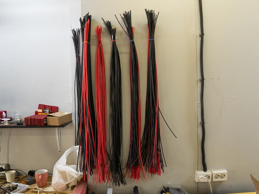 Plastic ties used in building drones hang from the wall over a workbench at Skyassist in Ukraine.