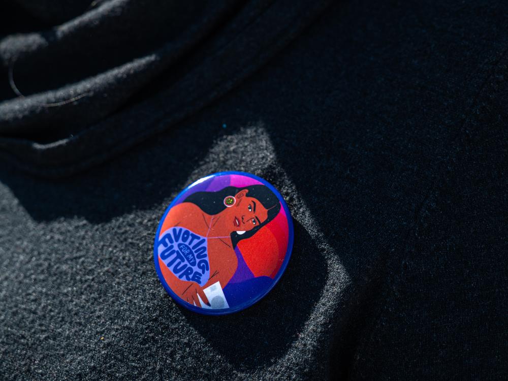 A woman wears a pin that reads 