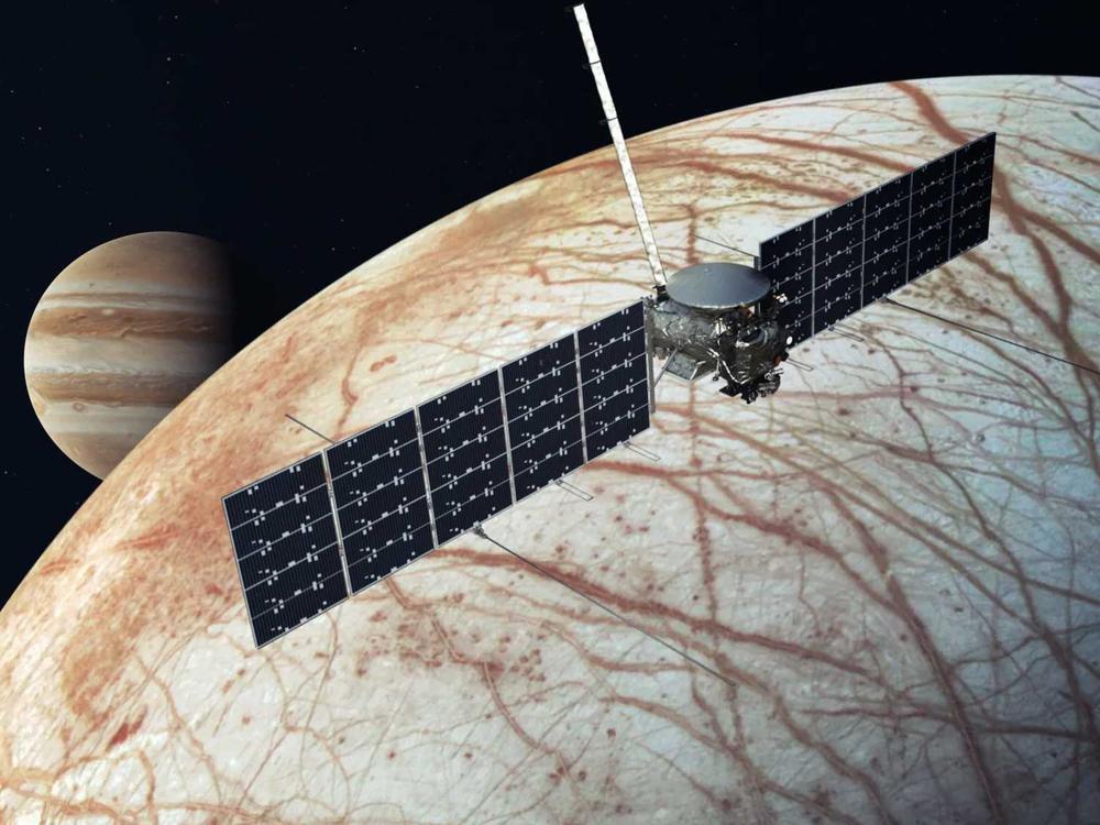 This illustration provided by NASA depicts the Europa Clipper spacecraft over the moon, Europa, with Jupiter at background left.