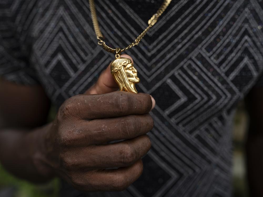 A person holds a gold necklace with the image of Jesus Christ on March 29, 2024, in the town of Juntas, Buenaventura, Colombia.