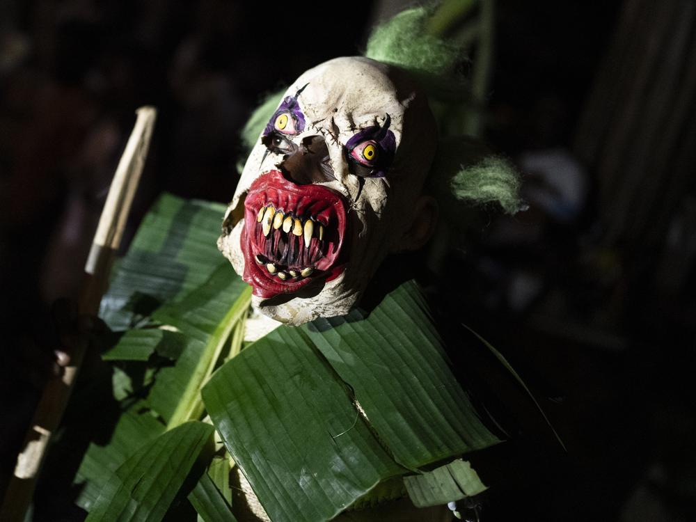The Manacillos make a representation of the Pharisee soldiers who collaborated with the death of Jesus Christ, dressed in local tree leaves and colorful wooden masks, at midnight on March 29, 2024, in the town of Juntas, Buenaventura, Colombia.