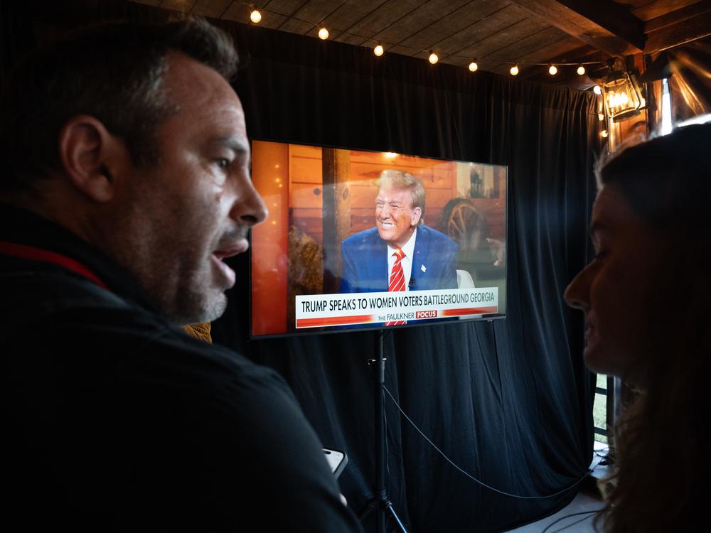 News photographers watch Republican presidential nominee and former President Donald Trump on-screen at a town hall event hosted by Fox News on Tuesday in Cumming, Ga.