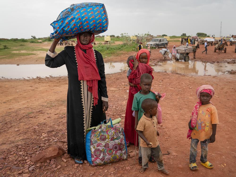 Awatif Zakaria Ahmad, 29, enters Chad from Sudan at the Adré border crossing, with her 5 children. She is carrying all of the family's belongings.