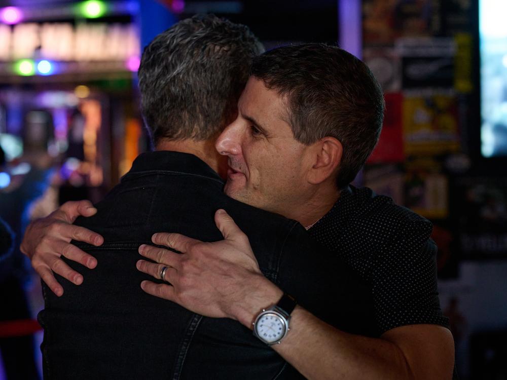 Louis Posen and Greg Harris embrace as they admire the Rock Hall exhibit.