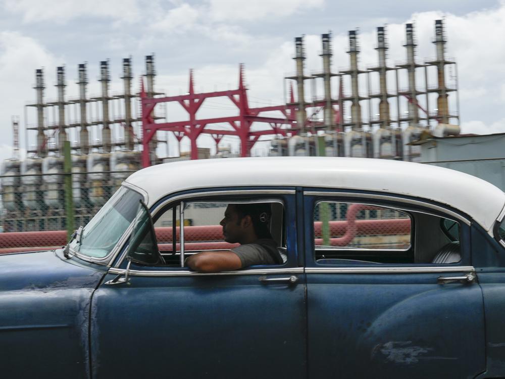 A person drives a classic American car past a floating generator that has not been producing electricity for days in Havana, Cuba, Friday, Oct. 18, 2024.