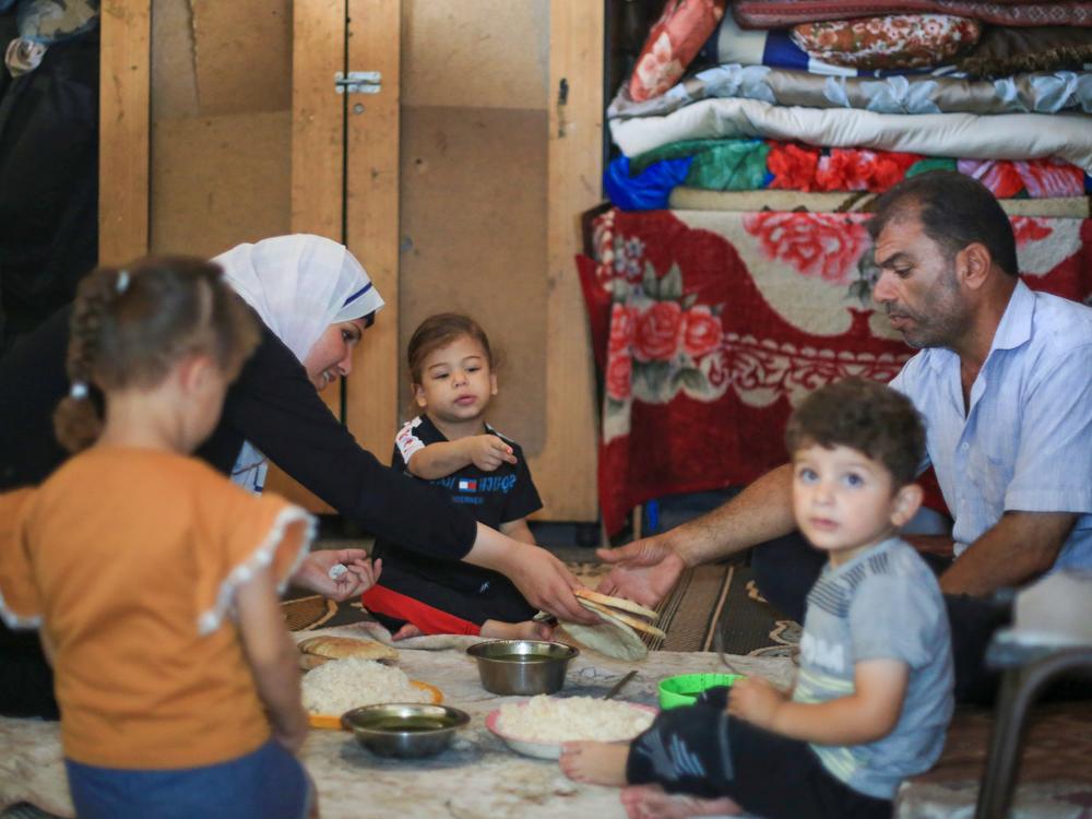Suad Ali Al-Nidr serves dinner to her two daughters, her father and her nephew. Her daughter Maysoon (center) has a severe wheat allergy, but most of the time, bread is the only thing they can find to eat.
