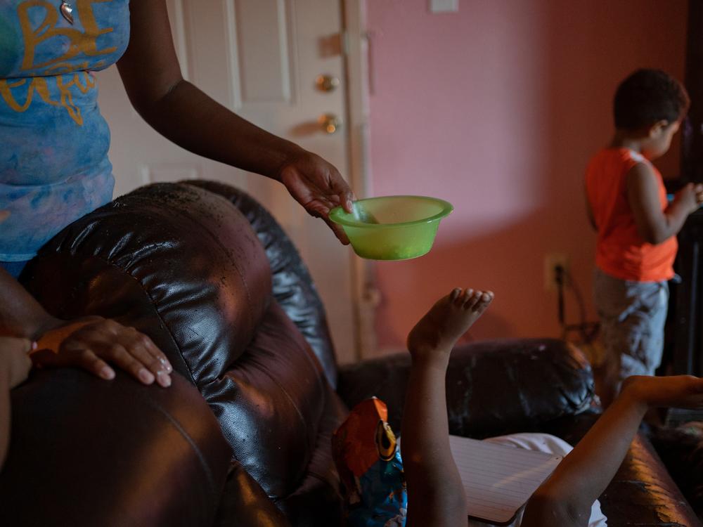 Emilia Lopez hands her 2-year-old son, Jose, a bowl of eggs while he plays on the living room couch of their apartment in Houston. A caretaker to seven children — five of her own, plus two from other family members — Lopez relies on donations from churches and food banks to feed them all.