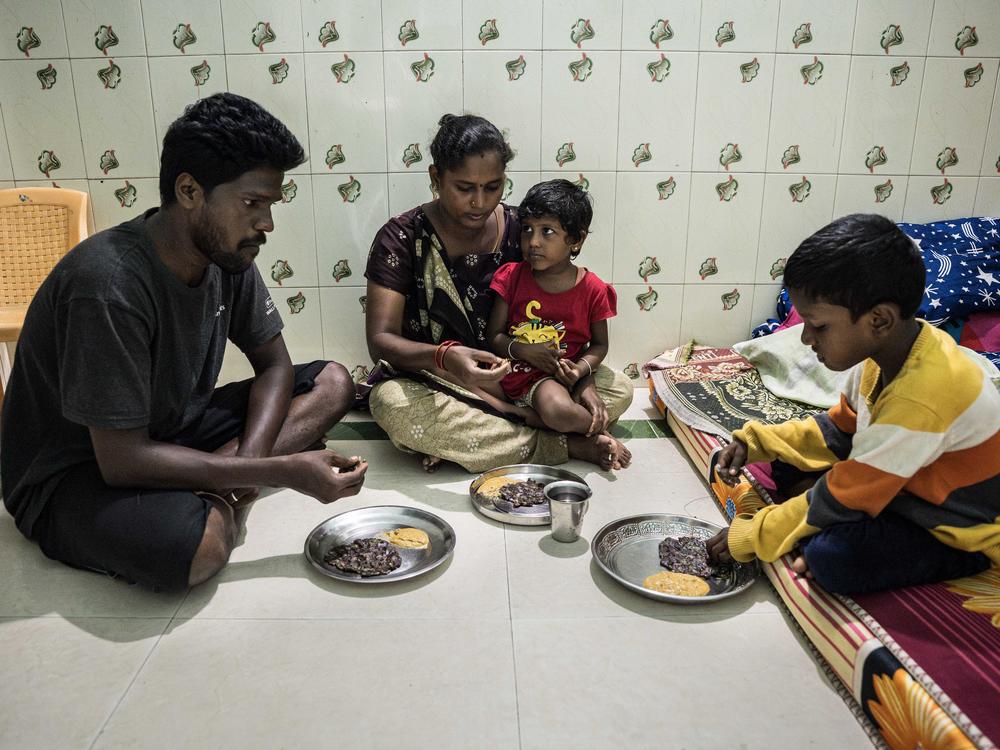 Srinivasan, Lakshmi and their children, Darshan, 5, and Sakshi, 4, eat a lunch of millet, a nutritious grain, and a serving of coconut chutney. In their tiny home, they sit on the floor of a room that serves as a bedroom, living room and dining room.