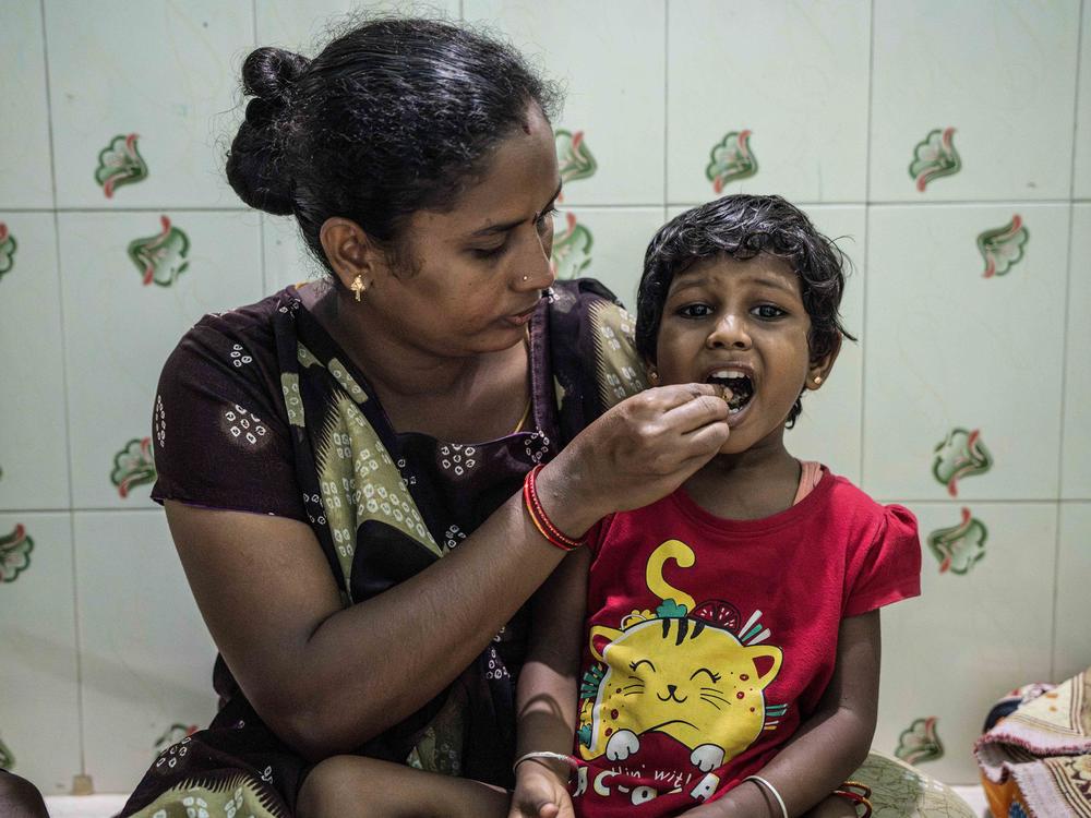 Lakshmi feeds lunch to her 4-year-old daughter, Sakshi: a flatbread made with millet, beans and curry leaves, along with a serving of coconut chutney.
