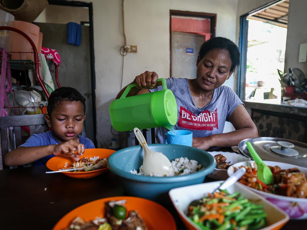 Rosnah, 48, eats with her son, Daniel, 5, after she has cooked an afternoon meal for her family in Orang Asli Sg Buloh, in Malaysia's Selangor state. 