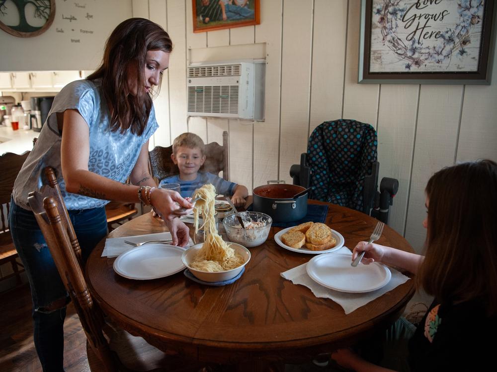 Caitlyn Kelly serves spaghetti and meat sauce to her children, Logan White (center), 6, and Annadale Norris, 10, in Greenville, Mississippi. Fruits and vegetables are hard to afford, she says.