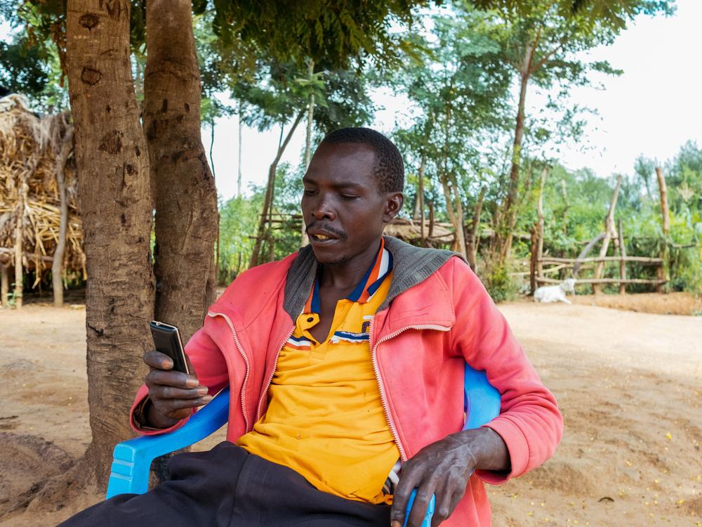 Miu, Kenya- June 6, 2024. Stephen Nzioka looks at the most recent messages received from the Kenya Agricultural Observatory Platform advising him on a spraying schedule for his crops.