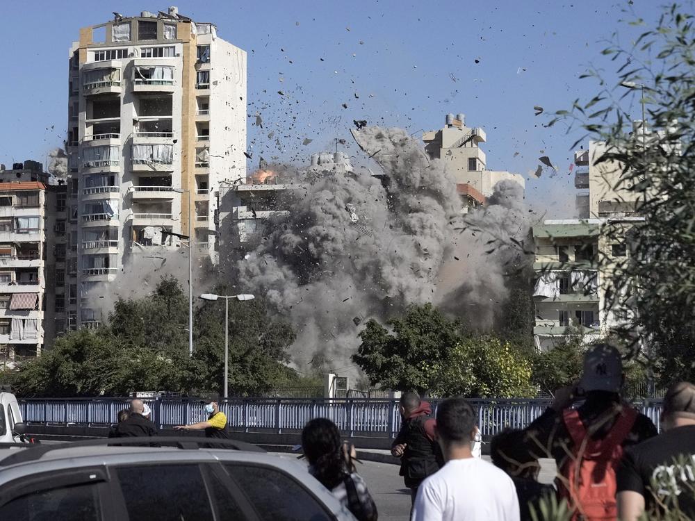 People watch a building collapse after being hit by an Israeli airstrike in Ghobeiri, Beirut, Lebanon, on Tuesday.