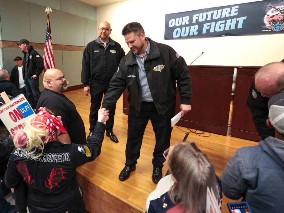 Jon Holden, the president of IAM District 751, shakes hands with Kat Kinckiner, a Boeing tool-room clerk for 15 years, during a strike rally in Seattle, Wash.