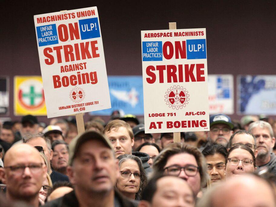 People hold sings during a strike rally for the International Association of Machinists and Aerospace Workers (IAM) at the Seattle Union Hall in Seattle, Wash., on October 15, 2024.