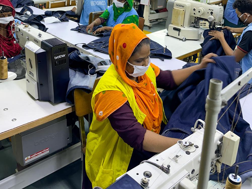 Ayesha Begum, in the foreground, is a garment worker in Bangladesh. She sews pockets on about 90 pairs of jeans an hour. The jeans will sell for about $50 each. She earns $134 a month.