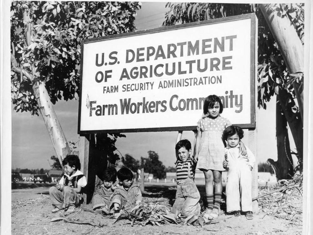 Children gather at the sign for one of the farm worker communities.
