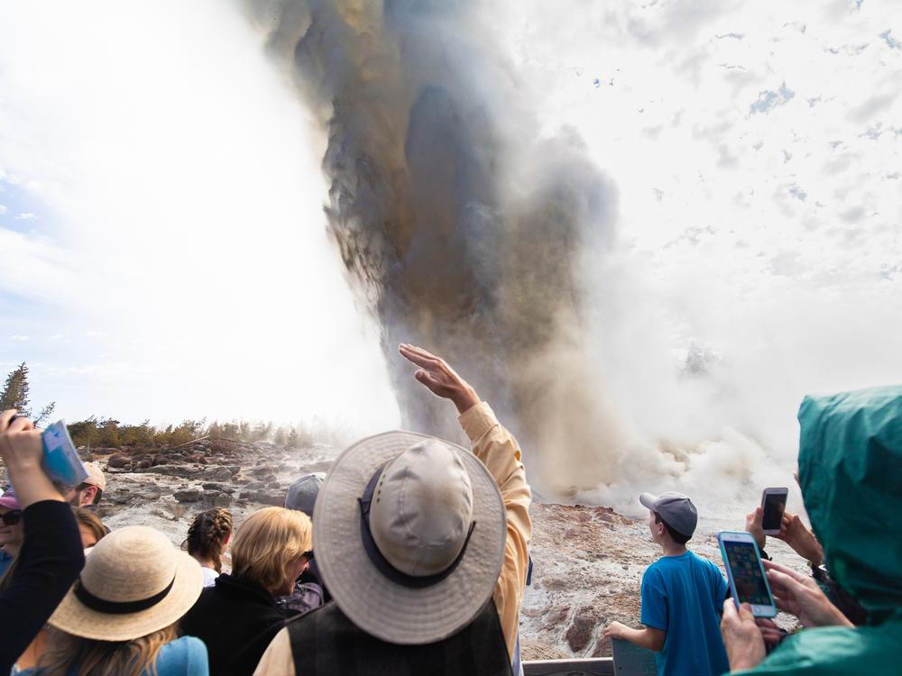 Wyoming, USA - A crowd of people witness the rare eruption of Steamboat Geyser, the largest active geyser in the world.
