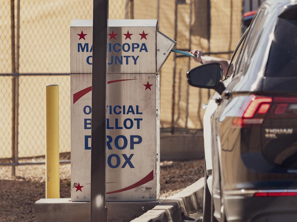 A voter drops a ballot into the drop box at the Maricopa County Tabulation and Election Center in Phoenix on Wednesday.