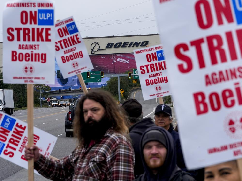 Boeing workers wave picket signs to passing drivers as they strike in Everett, Wash.. The machinists walked off the job more than six weeks ago as they bargain for higher pay and a return of their pension plan.
