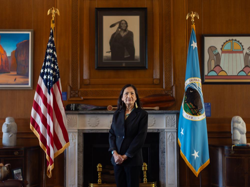 Interior Secretary Deb Haaland poses for a portrait in her office in the Department of Interior headquarters in Washington, DC on October 8, 2024. She selected each art piece, all made by Indigenous artists, that hangs on the wall behind her.