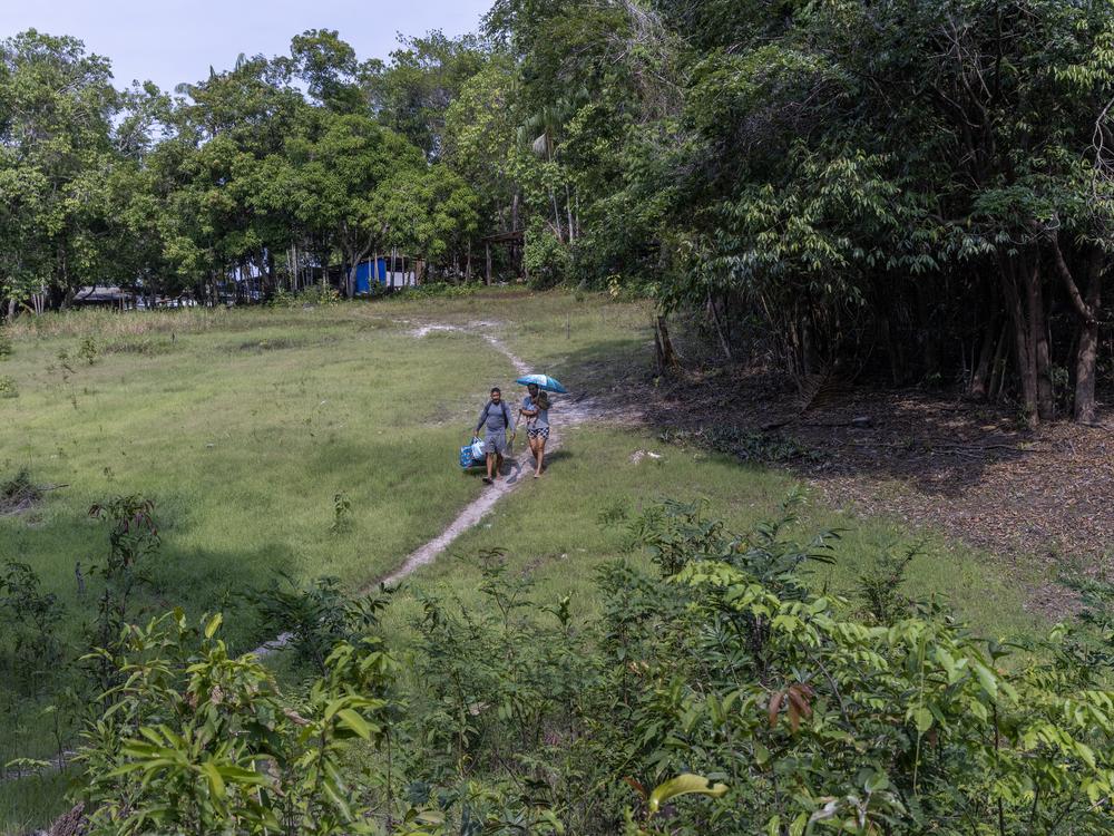 Janilce Rocha dos Santos, 45, holds her 5 months old baby boy Harley and walks with her husband Arlen Lavareda, 39, to the port where the transport boats stop during the dry season at Nossa Senhora do Livramento Community.