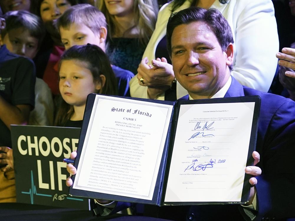 Florida Gov. Ron DeSantis holds up a 15-week abortion ban law after signing it on April 14, 2022, in Kissimmee, Fla.