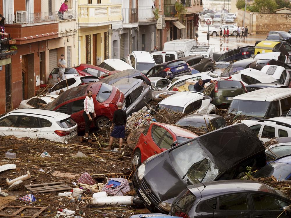 Residents look at cars piled up after being swept away by floods in Valencia, Spain, Wednesday.