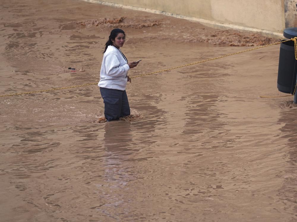 A woman walks through flooded streets in Valencia, Spain.