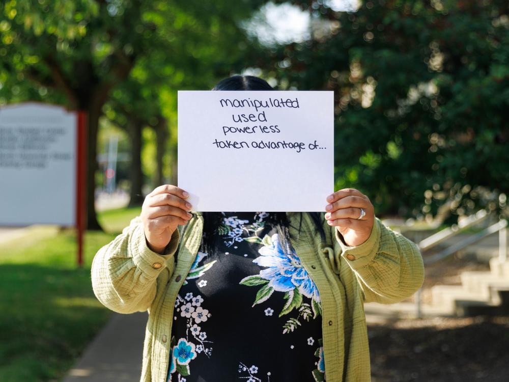 Daisy is a former crisis counselor at the local 988 call center in Bloomington, Ill. She holds a paper in front of her face listing emotions she felt when taking abusive calls while working there. She covers her face to maintain anonymity because she doesn’t want her personal or professional networks to know about the abuse. Daisy is the name she used with callers during her work shifts.