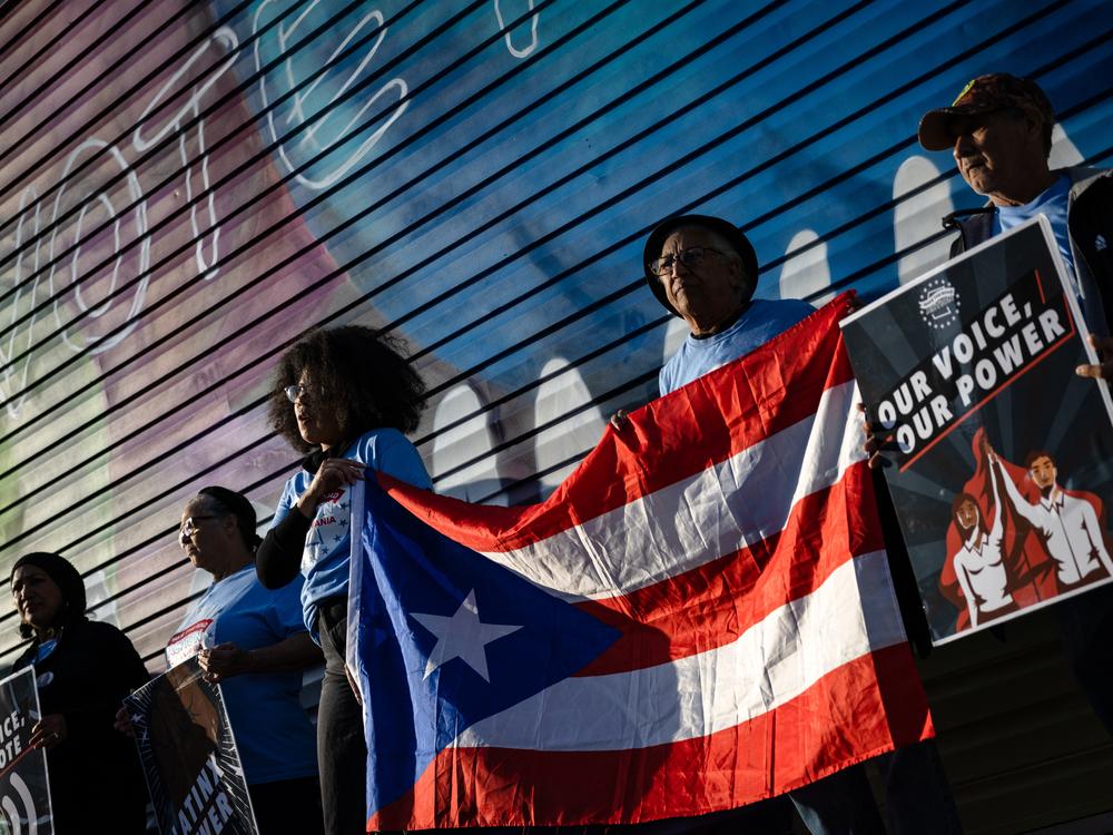 Supporters of Vice President Harris hold a Puerto Rican flag during a demonstration near the PPL Center ahead of a campaign rally with former President Donald Trump in Allentown, Pa., on Tuesday.