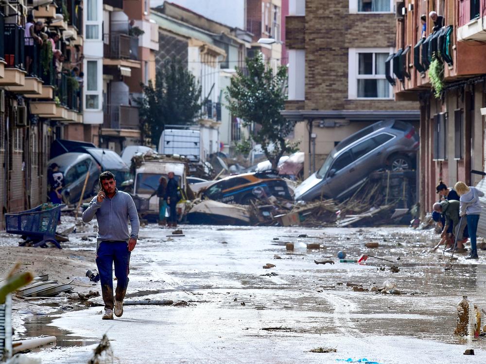 Residents are pictured next to cars piled in a street covered in mud following floods in Picanya, near Valencia.