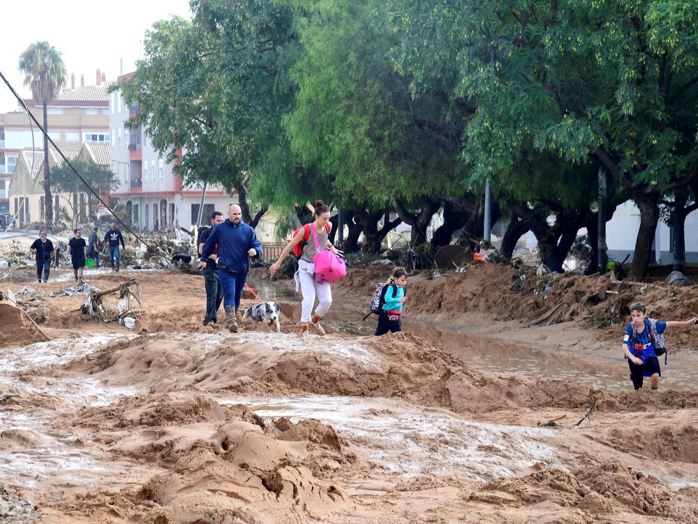 Family members walk in a street covered in mud in a flooded area in Picanya, near Valencia, eastern Spain.