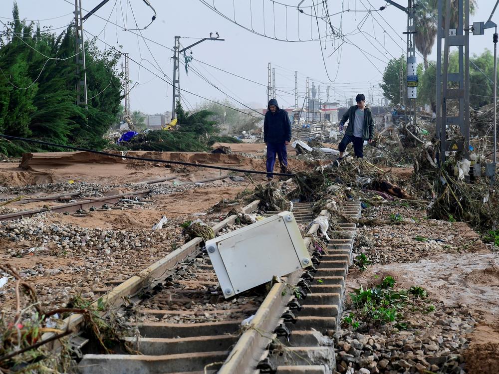 Residents walk among debris on a rail track following flood in Picanya, near Valencia, eastern Spain.
