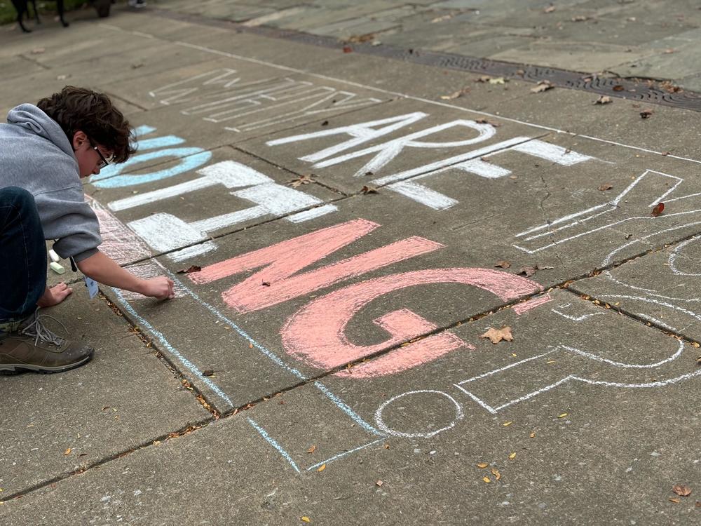 A student decorates the sidewalk with chalk ahead of a Get Out the Vote rally on the campus of Indiana University of Pennsylvania on Oct. 23.