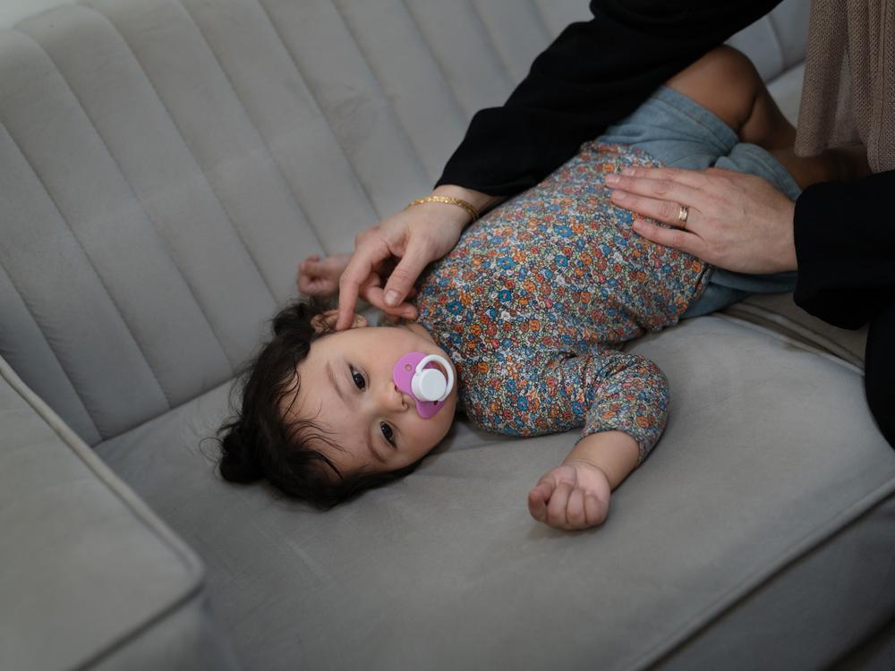 Soha Sakallah tries to coax her granddaughter, Mariam, to sleep on the sofa.