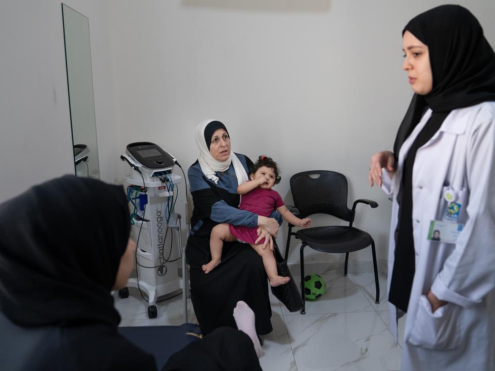 Mariam waits and plays with her grandmother during her mother's physical therapy appointment.