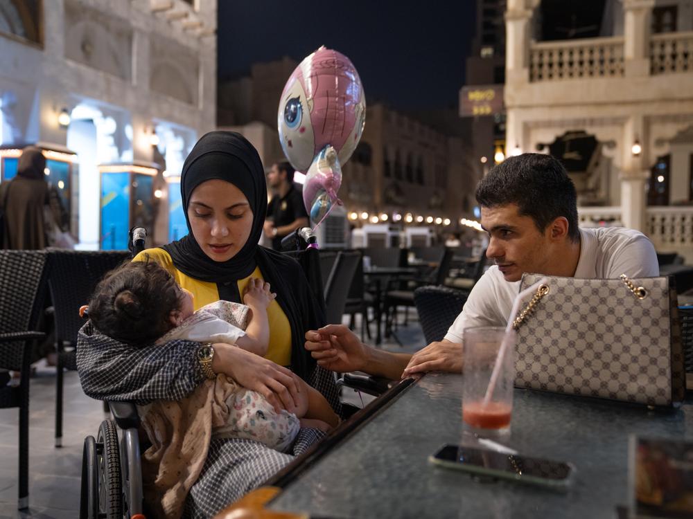 Raneem Hijazi (left) holds her baby, Mariam, while sitting next to her husband, Asaad Sakallah, at an outdoor cafe in Doha, Qatar. Until this summer, Hijazi was in Qatar by herself getting treatment. Now having the whole family around has livened up her life.