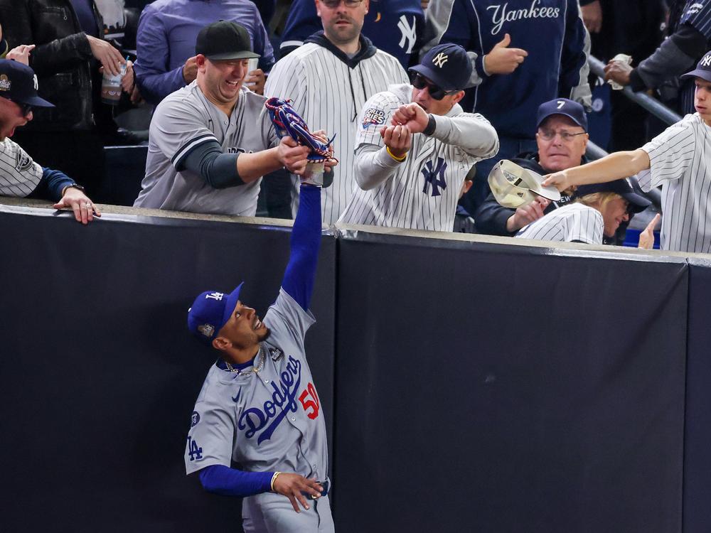 Fans interfere with Mookie Betts of the Los Angeles Dodgers as he attempts to catch a fly ball in foul territory during Game Four of the 2024 World Series against the New York Yankees at Yankee Stadium on Tuesday.