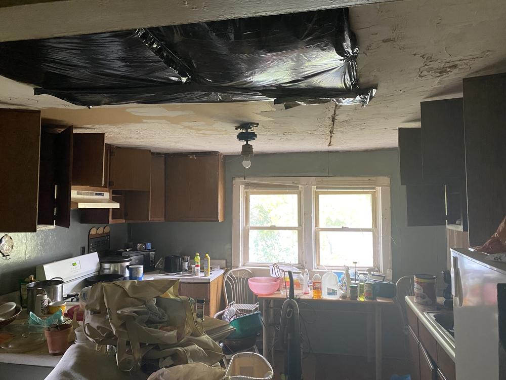 Velma Fishel's kitchen sags where the foundation had shifted, and a hole in the ceiling is covered with a garbage bag.