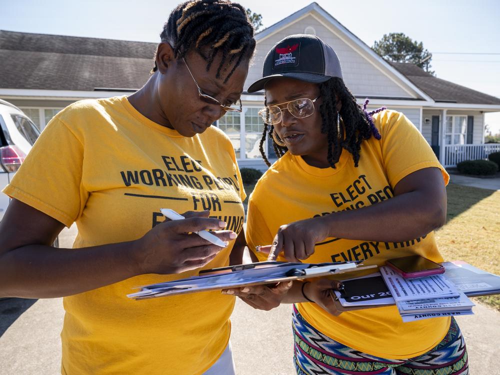 Andrea Farmer (left) and Alex Cook mark off homes they have visited on their app while canvassing in a neighborhood in Nashville, North Carolina in October.