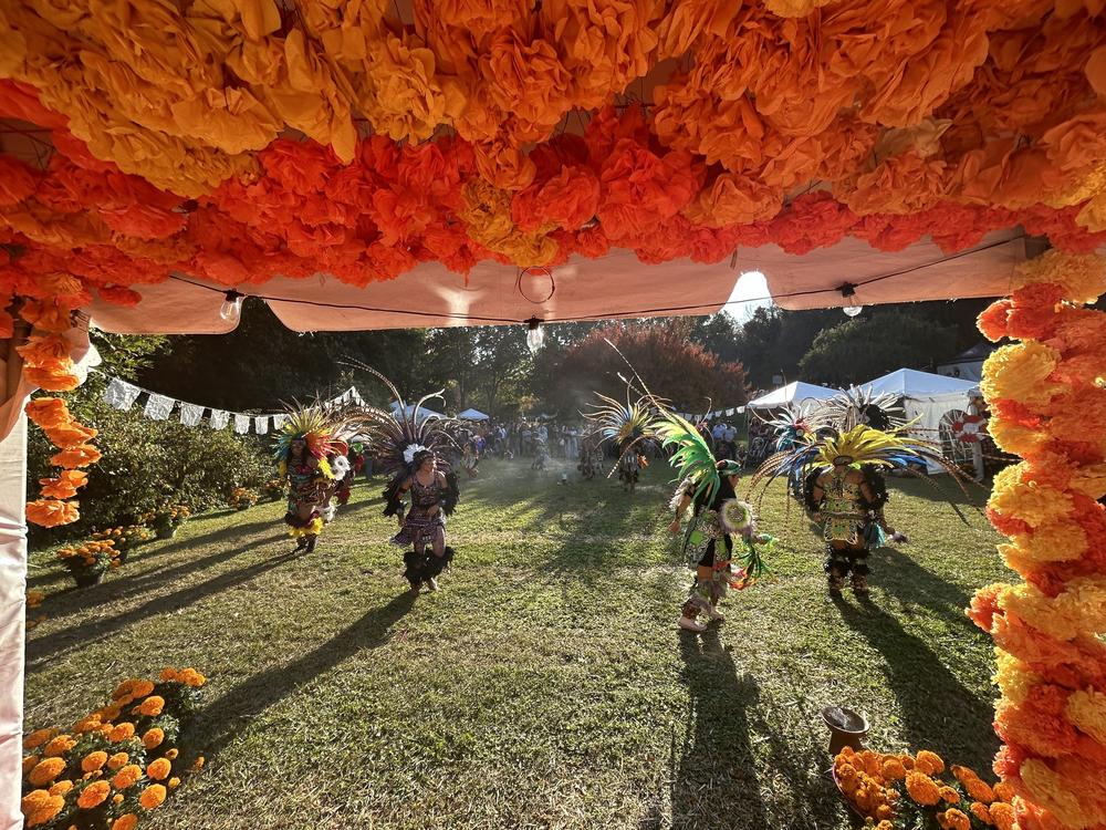 Aztec dancers circle the grounds at the Historic Oakwood Cemetery in Raleigh, North Carolina in front of Day of the Dead ofrendas.