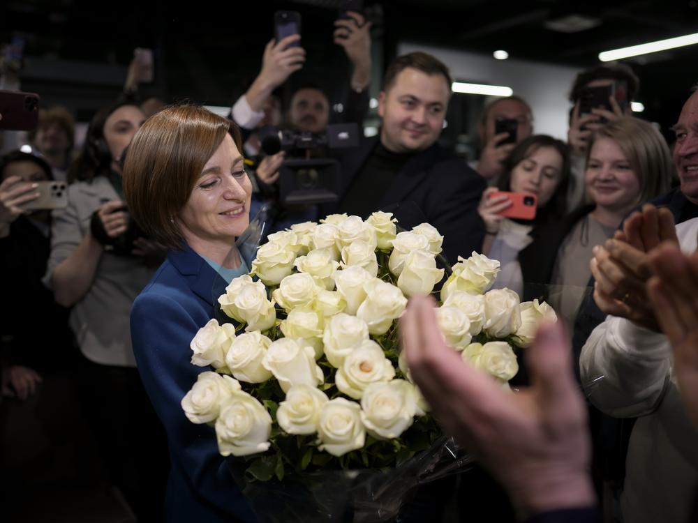 Moldova's President Maia Sandu smiles while holding a bouquet of flowers as she celebrates with supporters the preliminary results of the presidential election runoff, in Chisinau, Moldova, Sunday, Nov. 3, 2024.